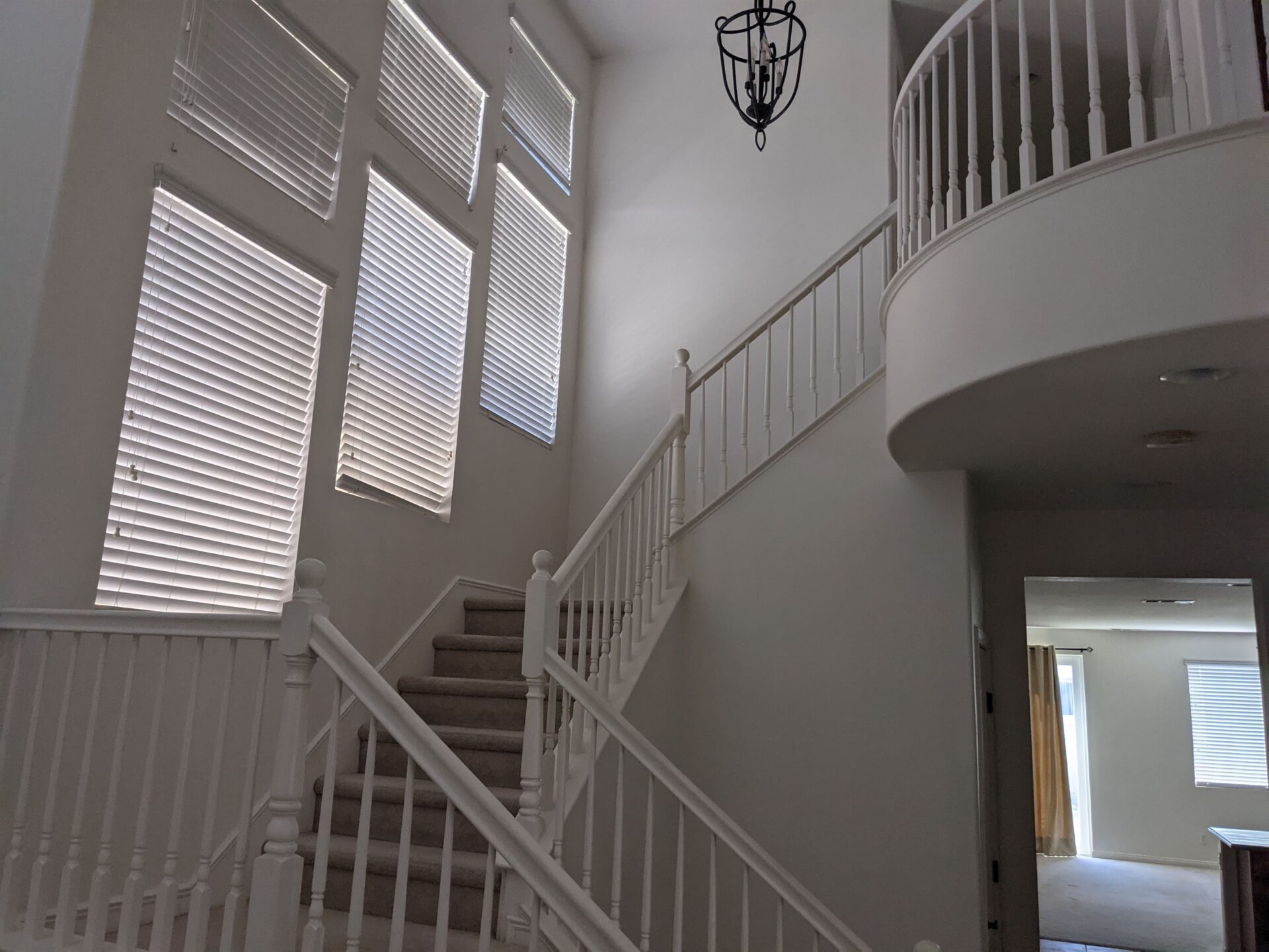 A white staircase with a light hanging from the top of it.