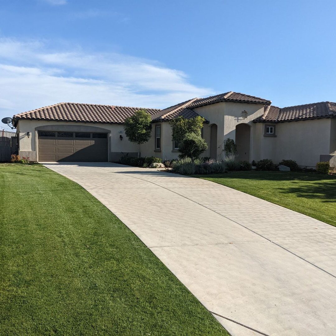 A house with a driveway and lawn in front of it.